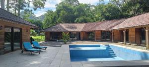 a house with a swimming pool and two blue chairs at El Sueño Belga in Golfito