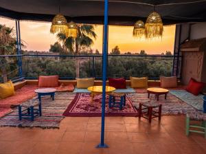 a patio with tables and chairs and a wall at Eco Farm Tayssir Marrakech in Marrakesh