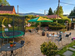 a patio with tables and chairs and an umbrella at Když nevíte kam, přijeďte k nám penzion D'Artagnan in Kořenov