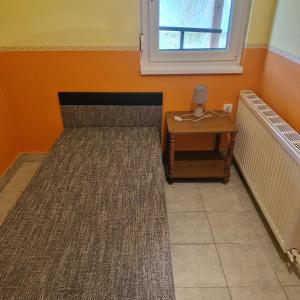 a room with a bed with a table and a window at Samu lakóház in Balatonberény