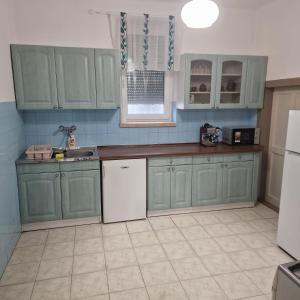 a kitchen with green cabinets and a white refrigerator at Samu lakóház in Balatonberény