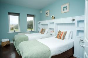 two beds in a room with blue walls and windows at Apartment 1 in Doolin