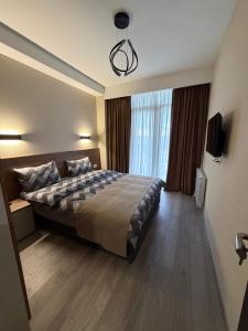 a bedroom with a bed and a large window at Relax Apartments in Crystal Residence Bakuriani in Bakuriani +1 photo