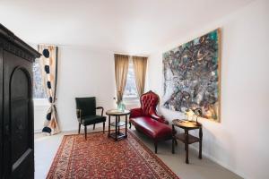a living room with a red chair and two chairs at Villa Beaulieu in St. Moritz