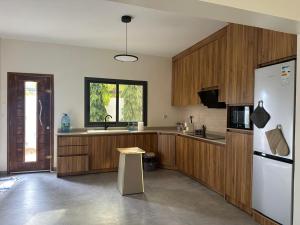 a kitchen with wooden cabinets and a white refrigerator at Ker Ar Mor - Villa 3 chambres avec piscine privée à Nguerigne in Sintiân
