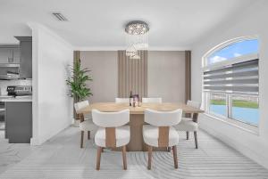 a dining room with a wooden table and white chairs at 6BR Villa Tropical Haven Private Pool & BBQ in Homestead