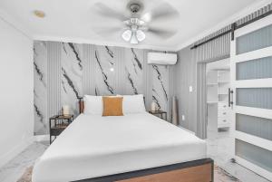 a bedroom with a white bed and a ceiling fan at 6BR Villa Tropical Haven Private Pool & BBQ in Homestead