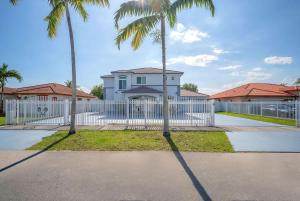 a white fence with palm trees in front of a house at 6BR Villa Tropical Haven Private Pool & BBQ in Homestead +40 photos