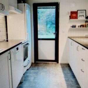 a kitchen with a door leading to a kitchen with a refrigerator at Bright, fully equipped property in Örebro in Örebro