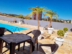 a patio with a table and chairs next to a pool at Palace Hotel Jacutinga JS in Jacutinga