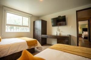 a hotel room with two beds and a flat screen tv at Hotel Omenia in Tequisquiapan