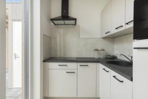 a kitchen with white cabinets and a sink at Sea & Forest Lodge in Oostkapelle