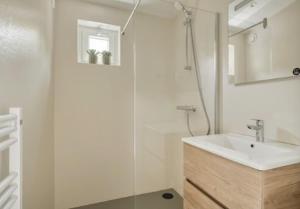 a white bathroom with a sink and a shower at Sea & Forest Lodge in Oostkapelle