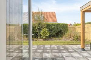 a sliding glass door of a yard with a fence at Sea & Forest Lodge in Oostkapelle +4 photos