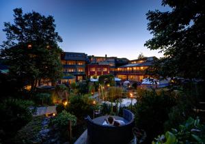 a person sitting in a tub in a garden at night at Hotel MY Kramerwirt in Geiersthal