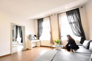 a woman sitting on a couch in a living room at Apartamenty Młyńska15 self check-in 24h in Katowice