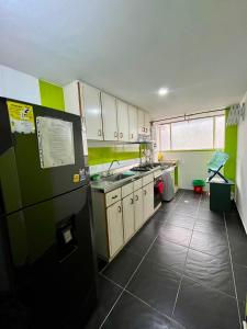 a kitchen with white cabinets and a black refrigerator at Apartamento Completo Sector Exclusivo De Zipaquirá in Zipaquirá