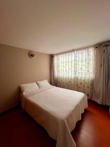 a bedroom with a white bed and a window at Apartamento Completo Sector Exclusivo De Zipaquirá in Zipaquirá
