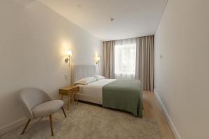 a bedroom with a bed and a chair and a window at Chalet Santo António in Sintra