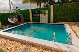 a swimming pool in a backyard with a hedge at Residence Cottages in Morogoro