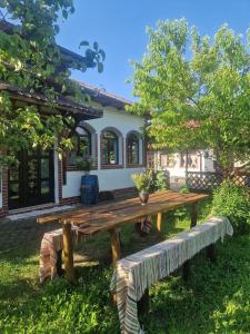 a wooden picnic table in front of a house at Casa Cuca Macai in Lăunele