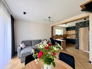 a living room with a couch and a table with flowers at Domek Veron 2 in Hańczowa +12 photos