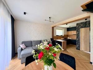 a living room with a couch and a table with flowers at Domek Veron 2 in Hańczowa