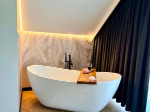 a white bath tub with a glass of wine in a bathroom at Domek Veron 2 in Hańczowa