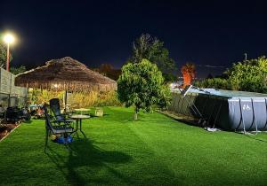 a yard with a table and a straw umbrella at לרניקה - יחידות אירוח in Qiryat Shemona