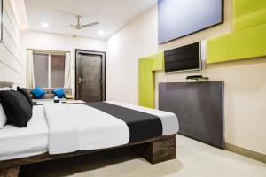 a bedroom with a bed and a flat screen tv at Super Townhouse Dewas City Formerly Utsav in Dewās