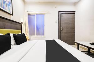 a bedroom with a large bed and a desk at Super Townhouse Dewas City Formerly Utsav in Dewās