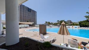 a pool with chairs and an umbrella next to a building at Sweet Escape with new heated pool in Playa Paraiso