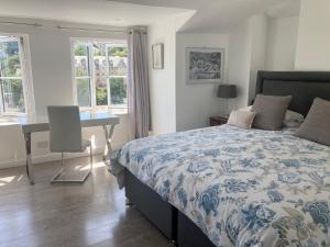a bedroom with a bed and a desk and windows at Sommersway Cottage in Torquay