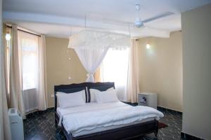 a bedroom with a bed with white sheets and a window at Musituni Luxury Villas in Diani Beach