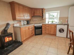 a kitchen with a stove and a fire in it at Shaws Hill Farmhouse in Ballymena