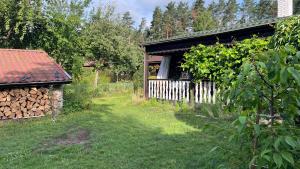 a building with a pile of wood next to a yard at Dacza Warmińska, domek letniskowy na jeziorem in Sząbruk