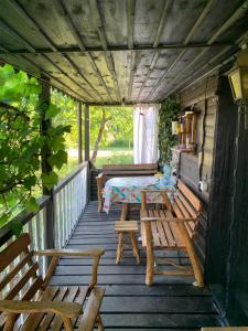 a wooden porch with a table and chairs on it at Dacza Warmińska, domek letniskowy na jeziorem in Sząbruk