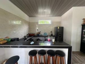 a kitchen with a counter with four bar stools at Casa Finca pasadia cerete in Cereté