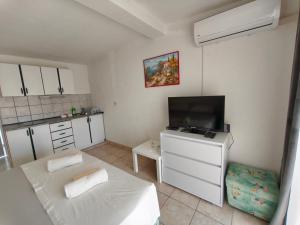 a small room with a television and a kitchen at Apartments Šešo B in Pag