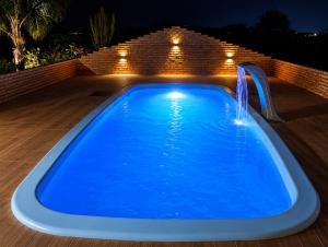 a blue swimming pool with a water fountain at Chácara Aconchegante com Piscina e Churrasqueira Perto do Ponto Turístico de Bezerros in Bezerros