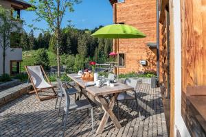 ein Holztisch mit einem grünen Sonnenschirm auf einer Terrasse in der Unterkunft Turrabuel in Parpan