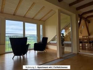 a living room with two chairs and a large window at Schads Bergheimat in Wertach