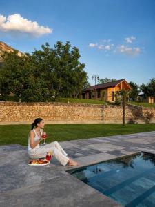a woman sitting on the ground next to a pool at Bujtina Kapinova in Berat