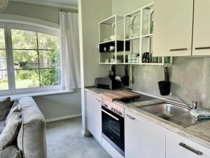 a kitchen with white cabinets and a sink and a window at Ferienwohnung FÜNF Hof Himmelgrün in Saal