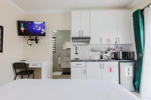 a kitchen with white cabinets and a table and a television at Edenvale corner in Edenvale