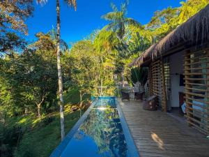 a swimming pool in front of a house with trees at Villa Pantai Secret Place in Miracatu