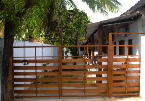 a wooden gate in front of a house with a tree at Arugambay Wave House in Arugam Bay