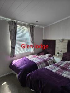a bedroom with two beds and a window with the words clear lodge at Glen lodge Craig Tara in Ayr