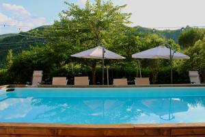 a swimming pool with two umbrellas and chairs at Casa di Cristian in Pian di Mulino