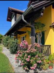 a yellow house with pink flowers in front of it at Privatzimmer in Steinfeld